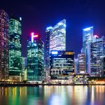 Buildings at night across water.