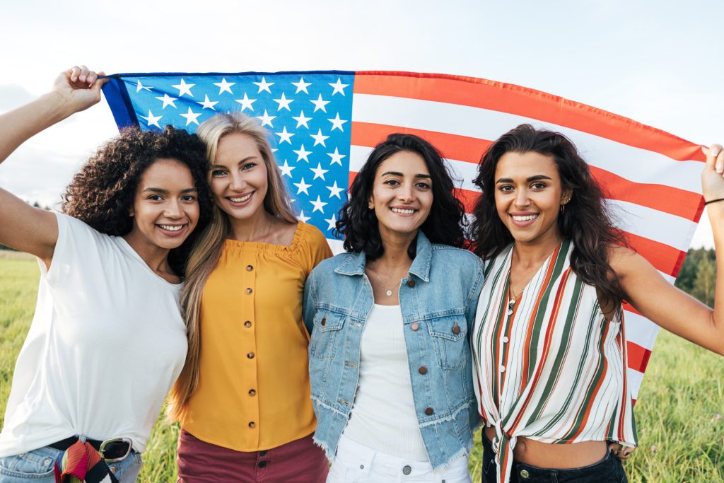 Four women displaying an American flag