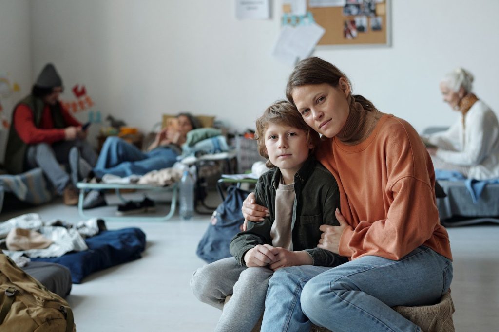 Alt title: woman and child in temporary housing. Alt text: woman and child sitting in small room.