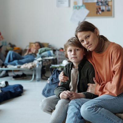 Alt title: woman and child in temporary housing. Alt text: woman and child sitting in small room.