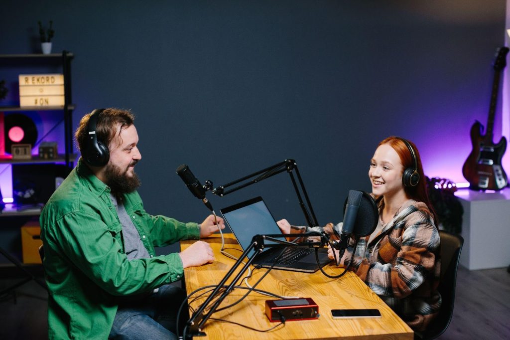 Two people at a table with mics and audio equipment.