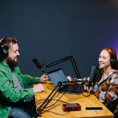 Two people at a table with mics and audio equipment.